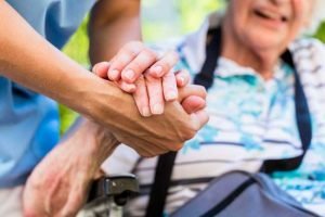 A kind caregiver holds the hand of an elderly parent