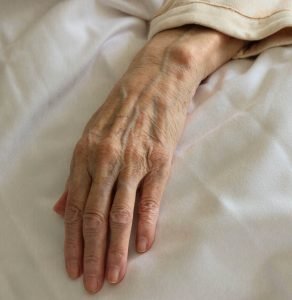 Left hand of an elderly person in bed