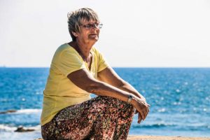 elderly woman sitting alone near ocean