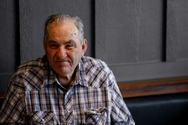 elderly man sitting in front of a black wall