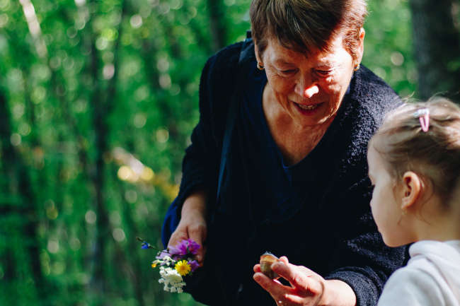 elderly woman holding flowers outside with her granddaughter