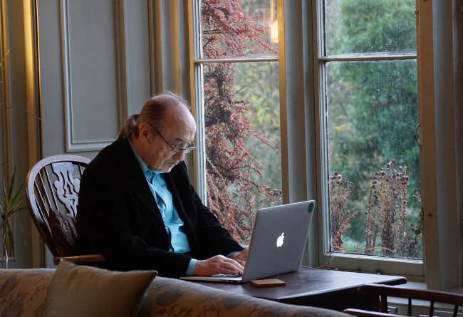 elderly man sitting at a table using a laptop