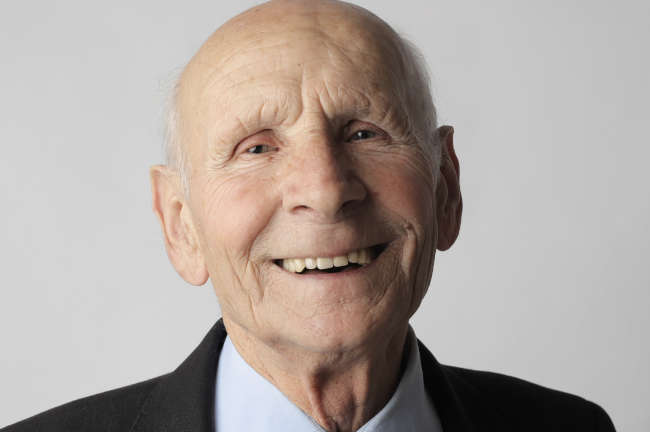 elderly man smiling and wearing a suit