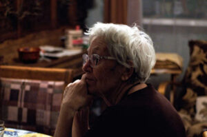 elderly woman sitting at a table thinking