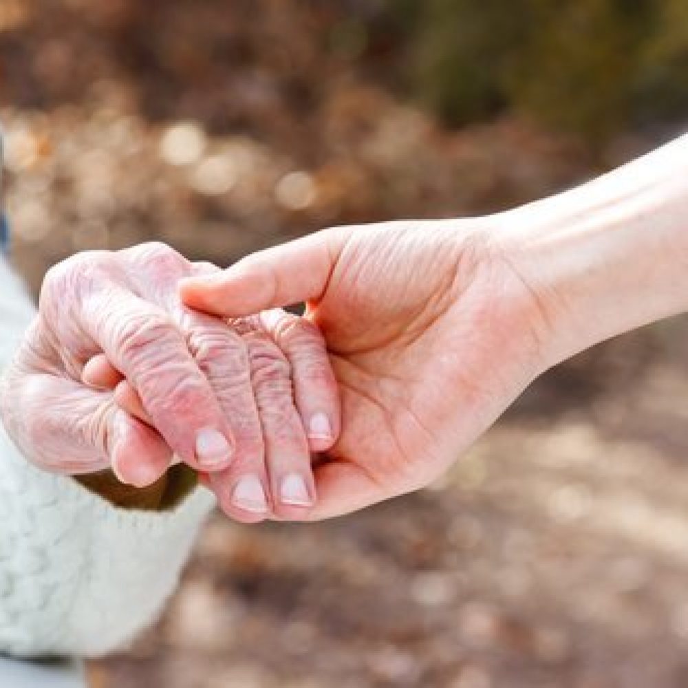 Senior Lady Holding Hands with Young Caretaker Senior Lady Holding Hands with Young Caretaker